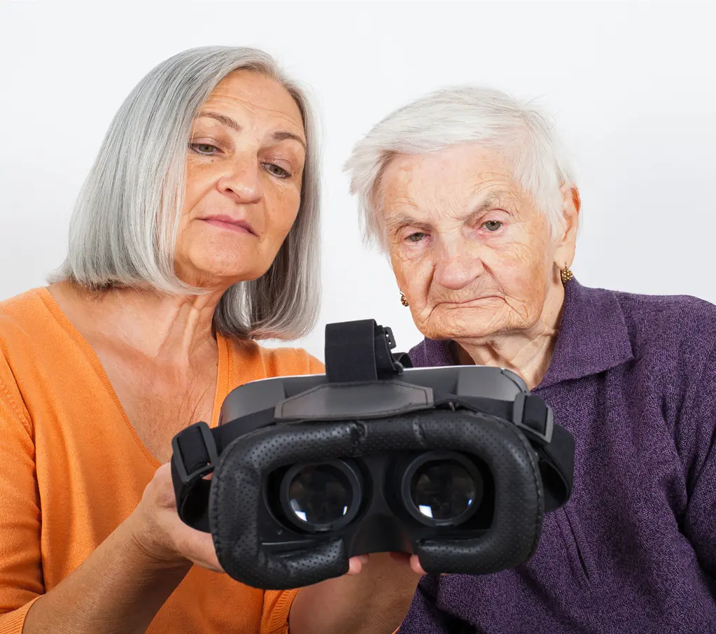 Two older women examining virtual reality headset.